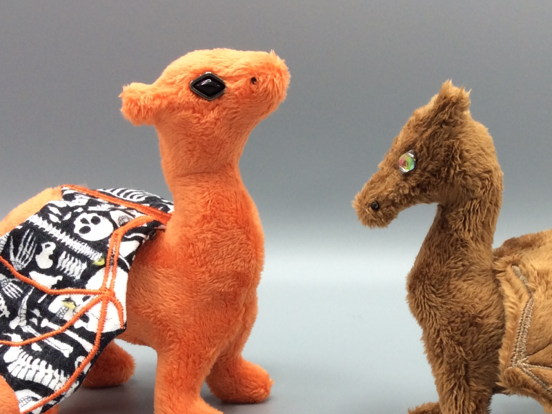 Two different sizes of dragons, one with a metal frame around the eye bead