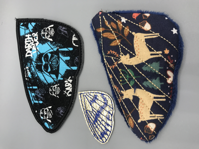 Three different hawk moth wings: one applique, one all-vinyl, and one turned plush.