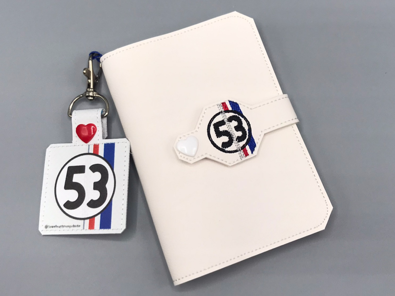 A mini composition book cover with the Love Bug &quot;53&quot; gumball as the snap closure, and as a charm hanging on the spine