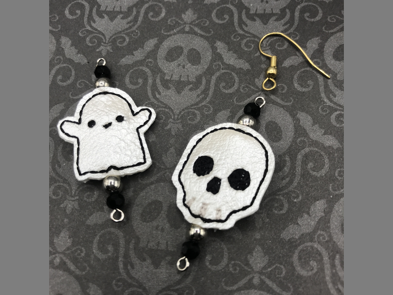 A tiny ghost and skull being made into dangle earrings.