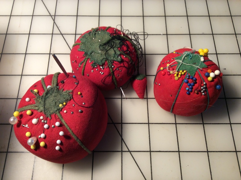 Three tomato-shaped pincushions, one with an attached &quot;strawberry.&quot;